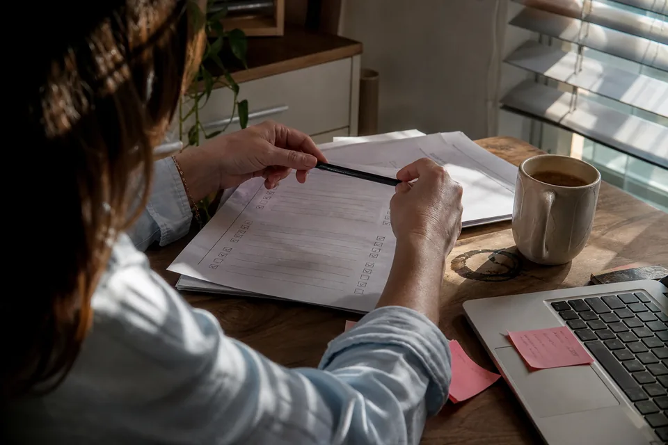 Implementation manager ticking off a printed customer onboarding checklist at her desk