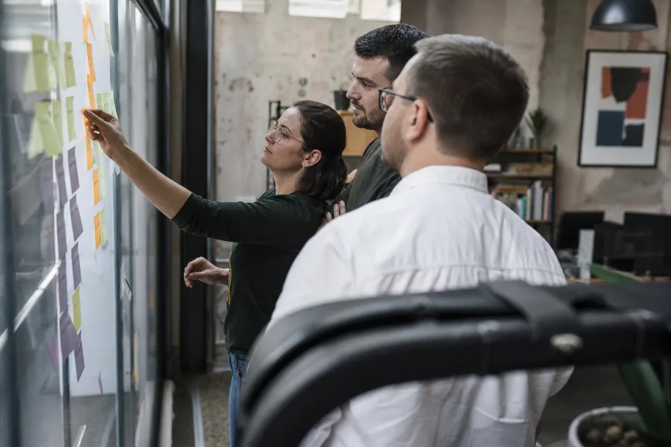 Implementation team mapping onboarding phases and dates on a glass wall
