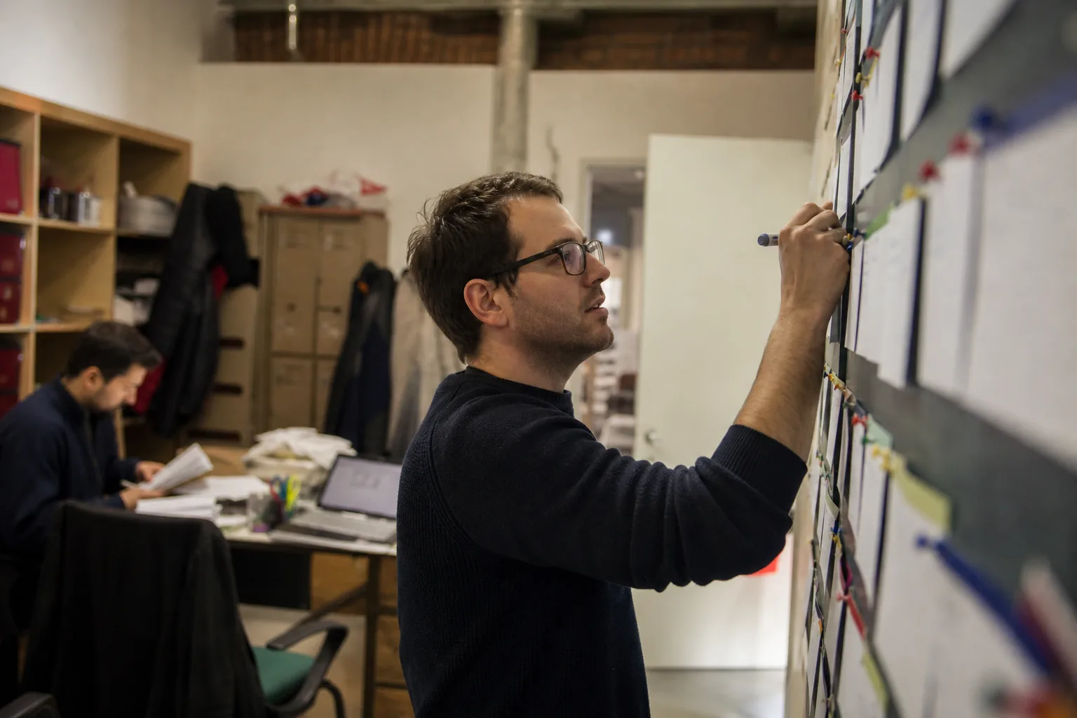 Implementation manager reviewing several customer projects on a wall-mounted board
